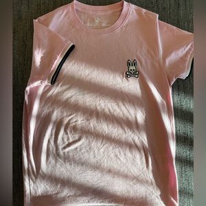 Baby pink Psycho Bunny shirt with black and white trim.